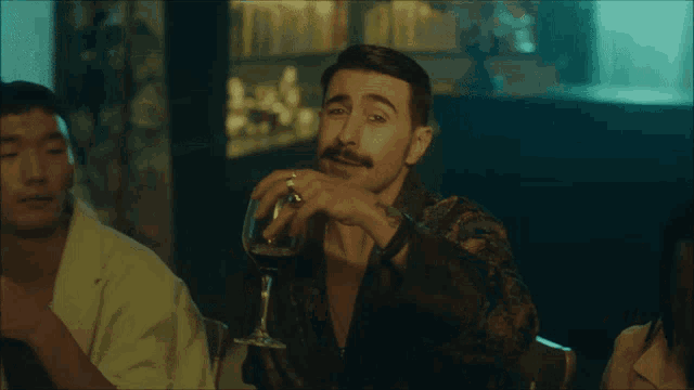 a man sitting at a table with a glass of wine