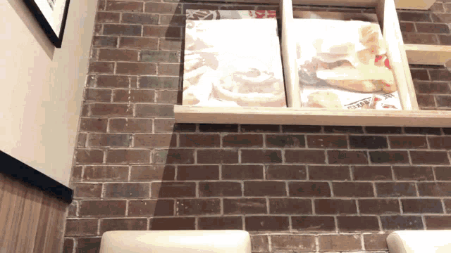 a brick wall with a wooden shelf with a picture of a sandwich on it