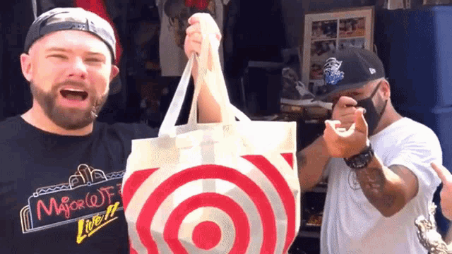 a man wearing a shirt that says " major q " holds a target bag