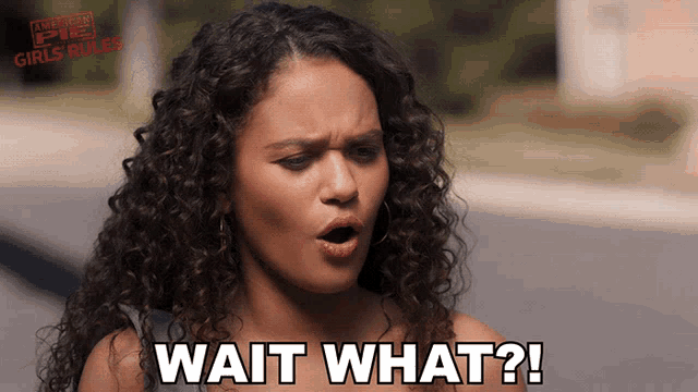 a woman with curly hair says wait what in front of a sign that says american pie girls rules