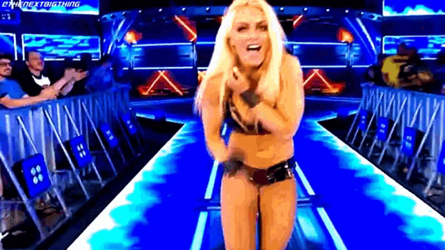 a woman in a bikini is standing in a wrestling ring and pointing at the camera .