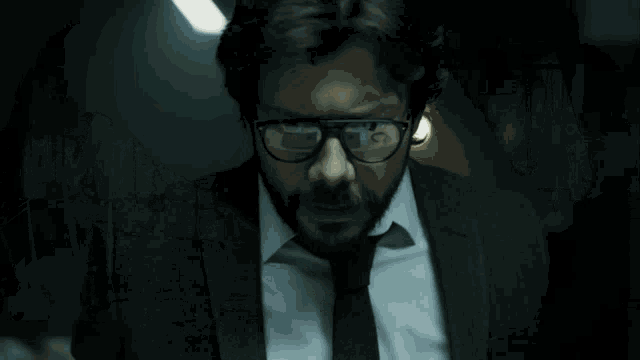 a man with glasses and a beard is wearing a suit