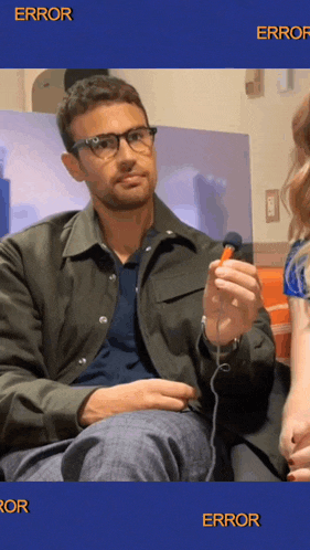 a man wearing glasses is holding a remote control in front of a screen that says error on it
