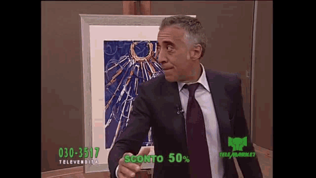 a man in a suit and tie is standing in front of a framed picture that says sconto 50 % in green letters