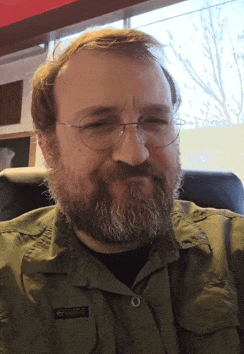a man with a beard wearing glasses and a shirt that says ' rugged ' on it