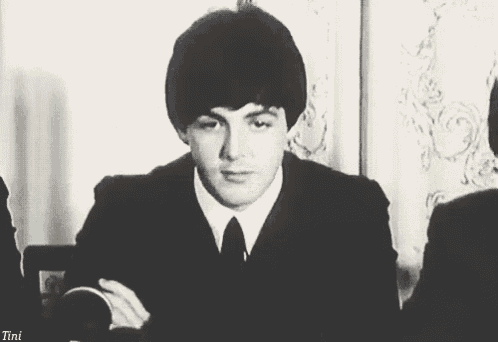 a black and white photo of a man in a suit and tie looking at the camera .