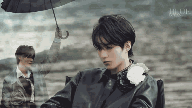 a man holding an umbrella in front of a blue ocean