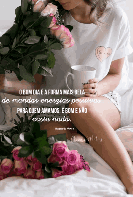 a woman sits on a bed holding a cup and a bouquet of pink roses