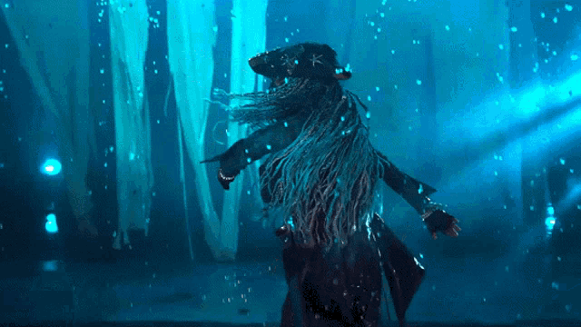 a woman in a pirate costume is dancing in a dark room with blue lights