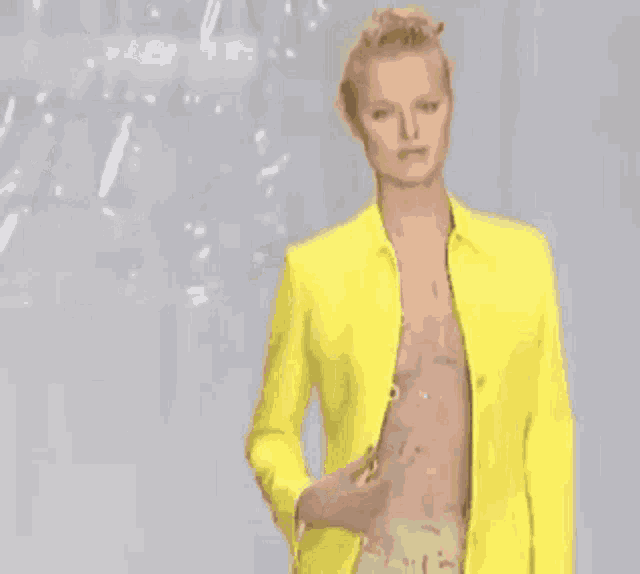 a man in a yellow jacket is walking down the runway