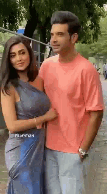 a man and a woman are posing for a picture on a sidewalk .