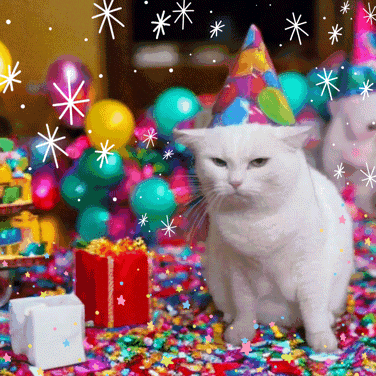 a white cat wearing a party hat is sitting on a pile of confetti