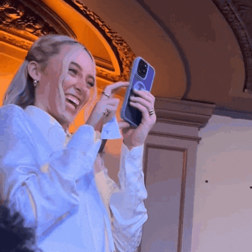 a woman in a white shirt is taking a selfie with her phone