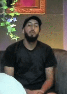 a man with a beard is sitting on a couch in front of a framed picture