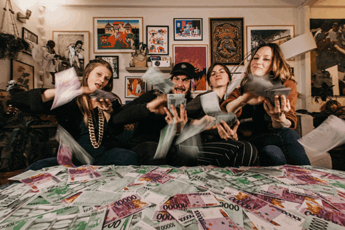 a group of people sitting on a bed with a pile of money that says 100000