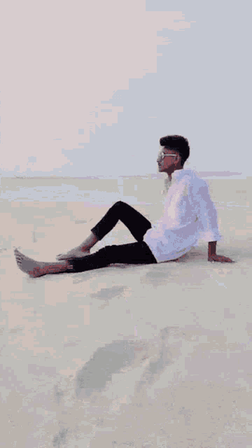 a young man in a white shirt is standing on a beach