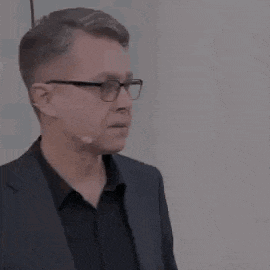 a man in a suit and glasses is wearing a microphone .
