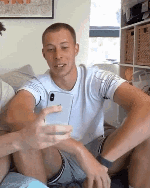 a man in a white shirt is taking a selfie with his phone
