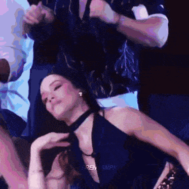 a woman in a choker is dancing on a stage while a man holds a microphone .