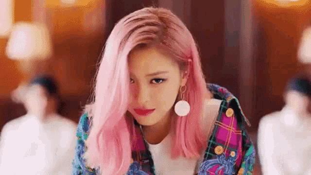 a woman with pink hair and earrings is wearing a plaid jacket and a white shirt .