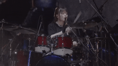 a woman is playing drums on a stage with a tama drum set