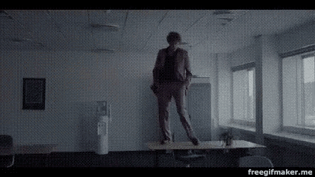 a man in a suit is standing on a table in an office