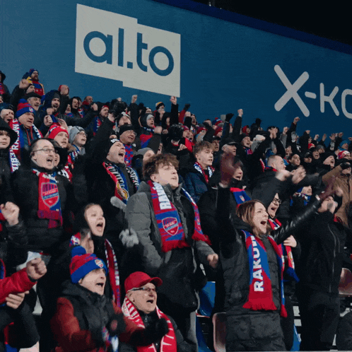 a crowd of people are cheering in front of a sign that says alto
