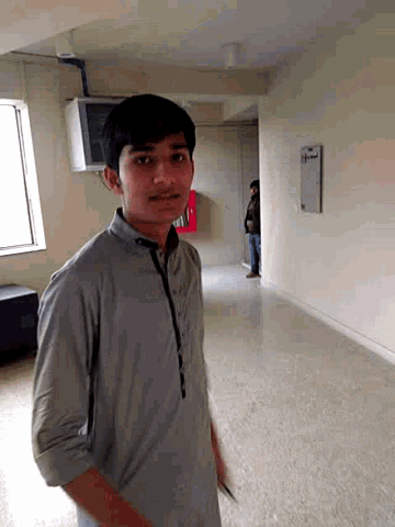 a man in a grey shirt stands in a room