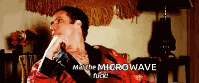 a man in a robe is sitting on a couch and talking to someone .