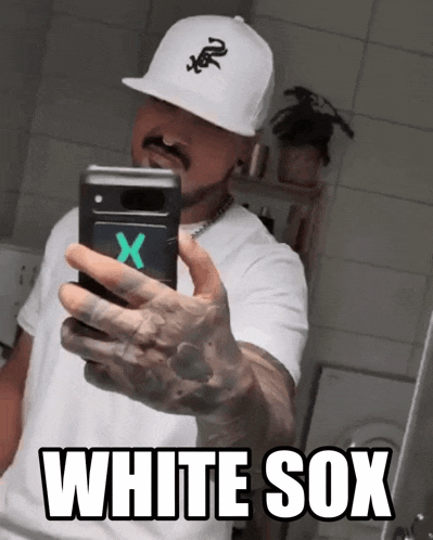 a man wearing a white sox hat takes a selfie with his phone
