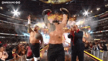 a wrestler holds up his championship belt in front of a crowd at a wrestlemania