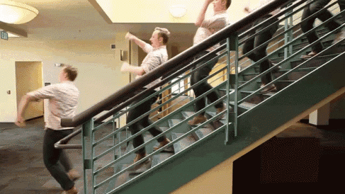 a group of people are walking up a set of stairs with a green railing