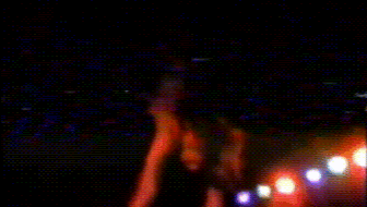 a blurry picture of a person dancing in a dark room with lights behind them