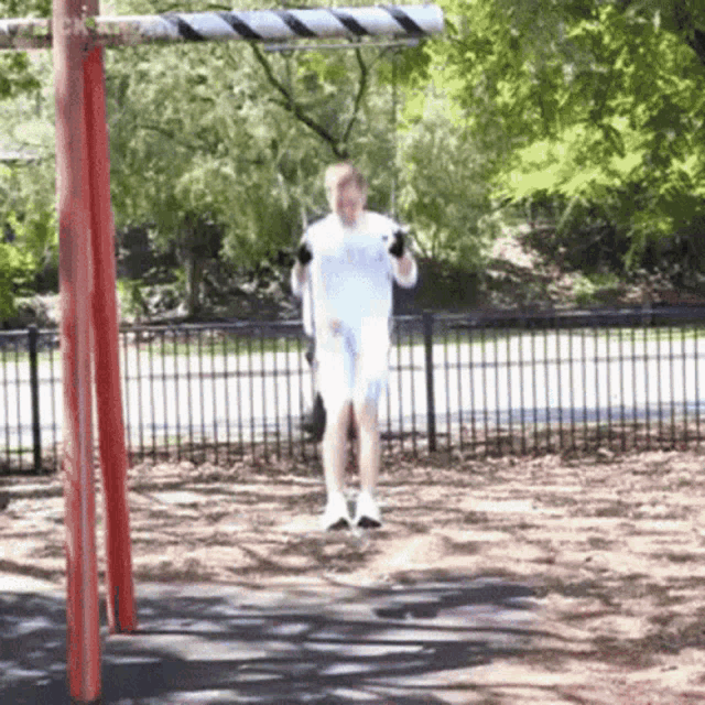 a man is swinging on a swing in a park