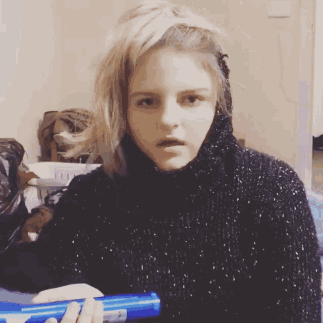 a woman in a black sweater is holding a blue container
