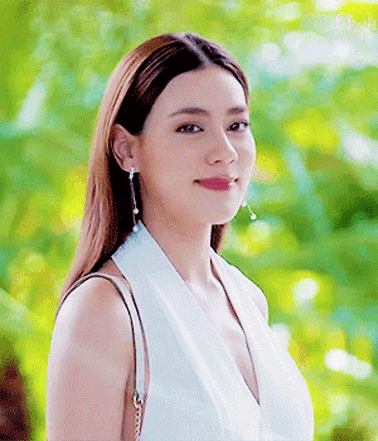 a woman is wearing a white top and earrings