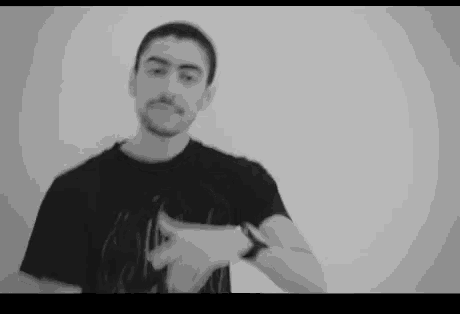 a man wearing a black t-shirt and a watch is pointing at something .