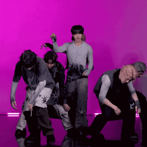 a group of men are dancing in front of a pink background