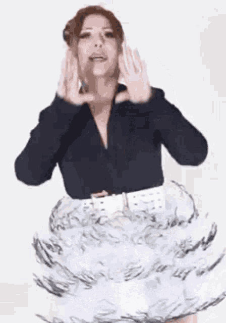 a woman is wearing a black shirt and a white skirt and making a funny face .