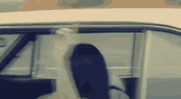 a woman is sitting in the driver 's seat of a car and looking out the window .