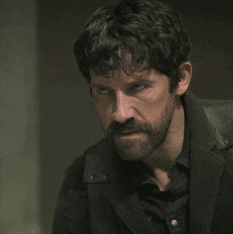 a man with a beard wearing a black jacket looks at the camera