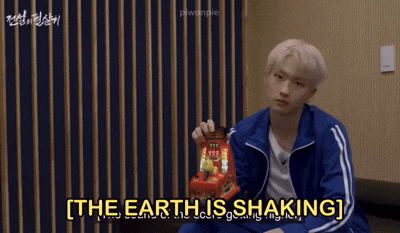 a man in a blue jacket is holding a toy and the words the earth is shaking are above him