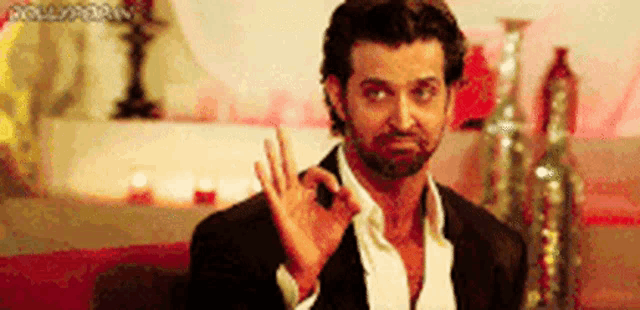 a man with a beard is giving the ok sign with his hand .