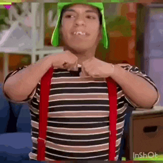 a man wearing a green hat and red suspenders is standing in a living room .