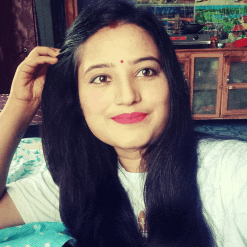 a woman with a red dot on her forehead smiles for the camera