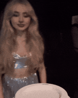 a woman in a blue dress holds a white plate