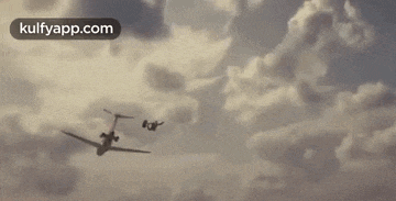 a man is flying through the air next to a small plane .
