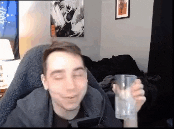 a man is sitting in a chair holding a glass of water in a living room .