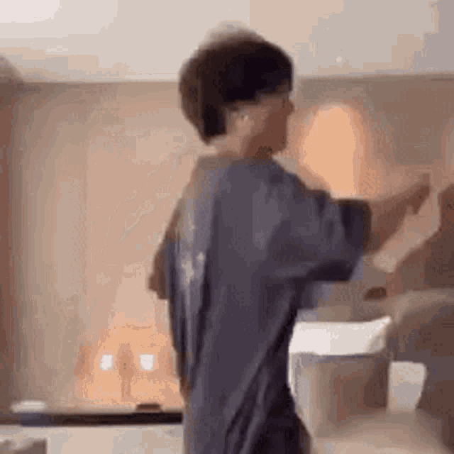 a man in a blue shirt is standing in a room .