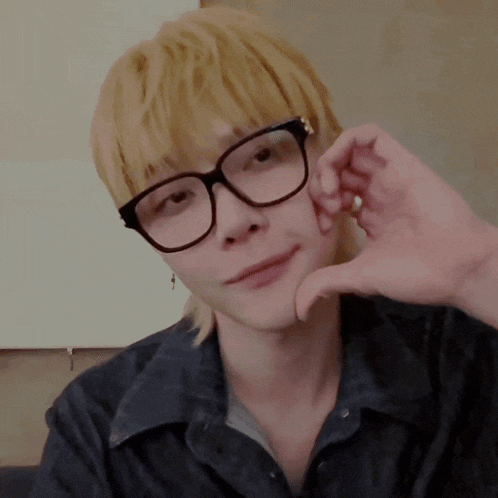 a person wearing glasses making a heart shape with their hands